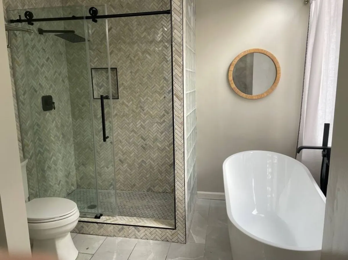 A spa-like bathroom with a freestanding bathtub, a sleek glass shower, and a round mirror, set in a tranquil, well-lit ambiance. Perfect for relaxation and self-care routines after a night out.